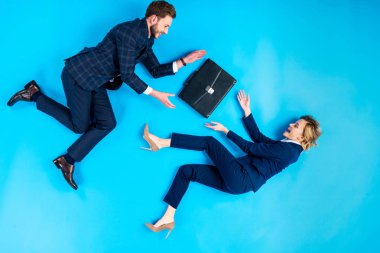 Evrak çantası üzerinde mavi arka plan ile poz takım elbiseli mutlu çift