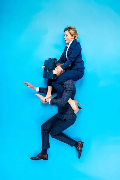 男子抱在肩膀上震惊的女人与公文包在蓝色背景 — 图库照片