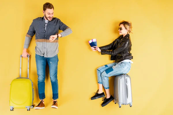 Woman Sitting Valise Tickets While Man Looking Watch Yellow Background — Stock Photo, Image