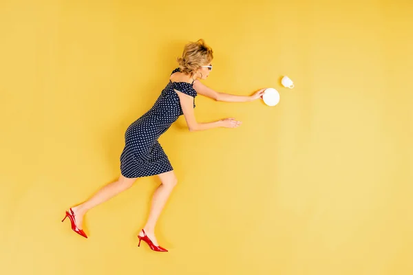 Blonde Vrouw Jurk Met Schotel Kopje Liggend Gele Achtergrond — Stockfoto