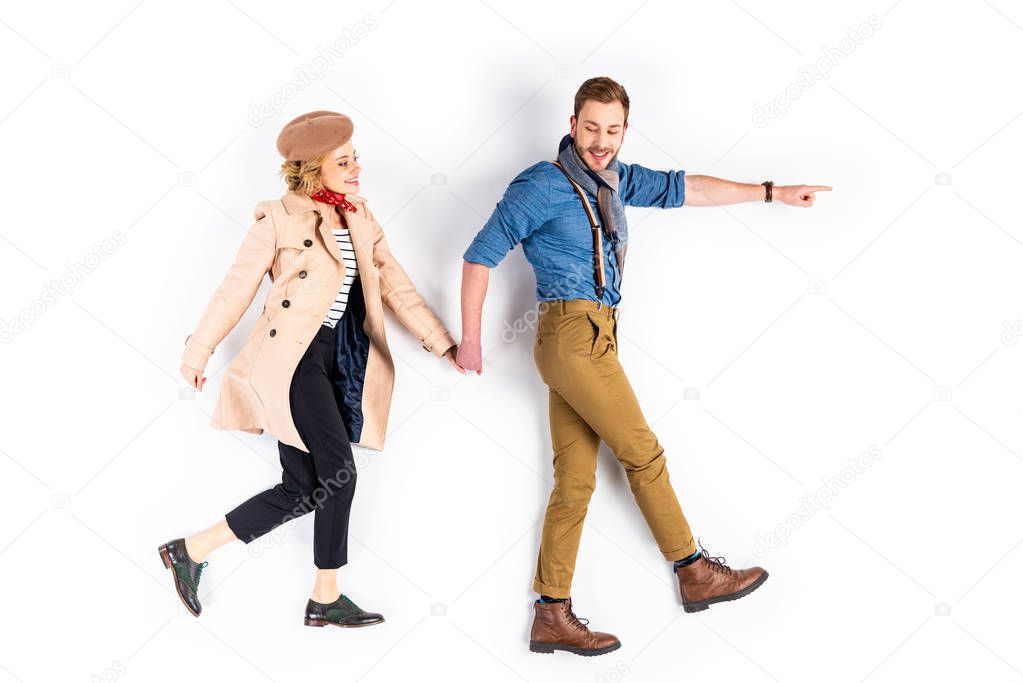 Excited couple holding hands and walking on white background