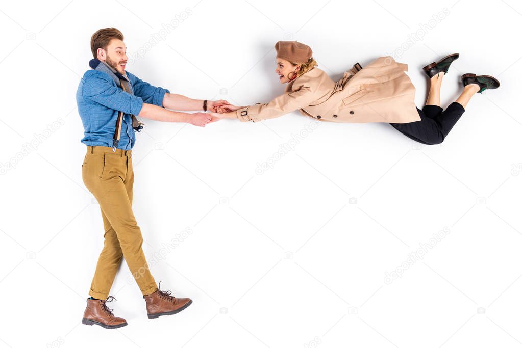 Happy couple in casual clothes holding hands on white background