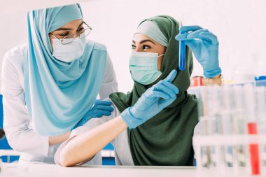 kadın Müslüman bilim adamları tıbbi maske cam tüp ile reaktif sırasında holding kimya laboratuvarında deney