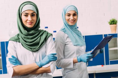 güzel kadın Müslüman kimyagerler hijab geçti silah ve laboratuvar kamerada bakarak Pano içinde