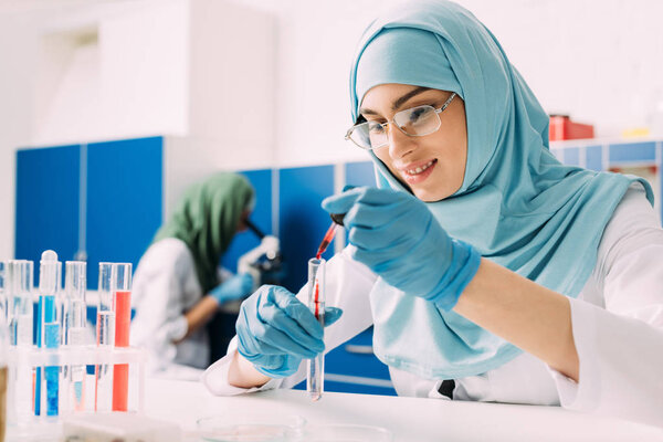 female muslim scientist adding blood in test tube in laboratory