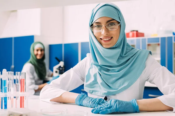 Scientifique Musulmane Souriante Avec Éprouvettes Regardant Caméra Pendant Expérience Laboratoire — Photo