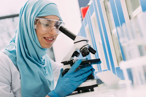 Científica Musulmana Sonriente Mirando Través Del Microscopio Durante Experimento Laboratorio —  Fotos de Stock