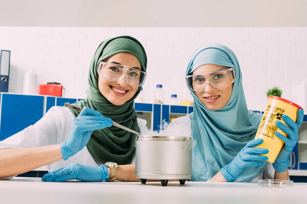 мусульманские ученые в очках, смотрящие в камеру во время экспериментов с сухим льдом в химической лаборатории
