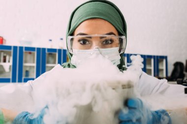 Kuru buz laboratuvar ile deneme yaparken kameraya bakarak kadın Müslüman bilim adamı