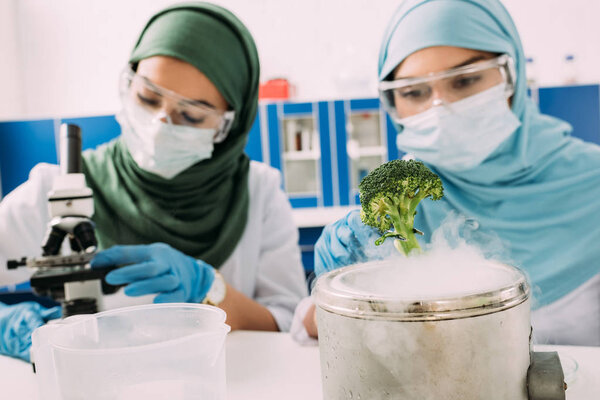 female muslim scientists experimenting with broccoli and dry ice in chemical laboratory