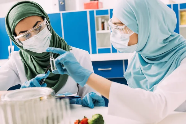 Cientistas Muçulmanos Fêmeas Máscaras Médicas Segurando Ampola Vidro Durante Experimento — Fotografia de Stock