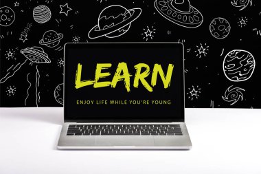 laptop on table with enjoy life while you are young and learn lettering on screen with white space illustration on black  clipart