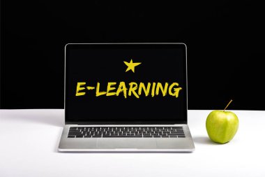 taze yeşil elma ve e-öğrenme harflerle ve siyah izole ekranda yıldız içeren tablo üstünde laptop