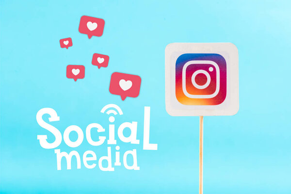 card with instagram logo and social media lettering with heart icons isolated on blue