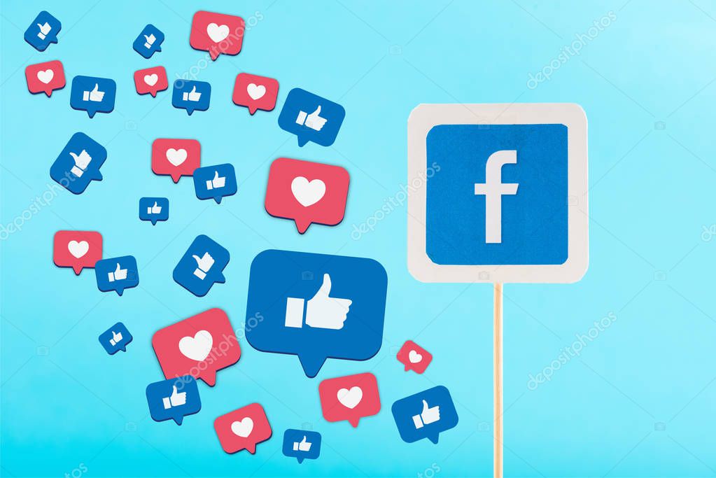 Card with facebook logo and thumbs up and hearts signs isolated on blue