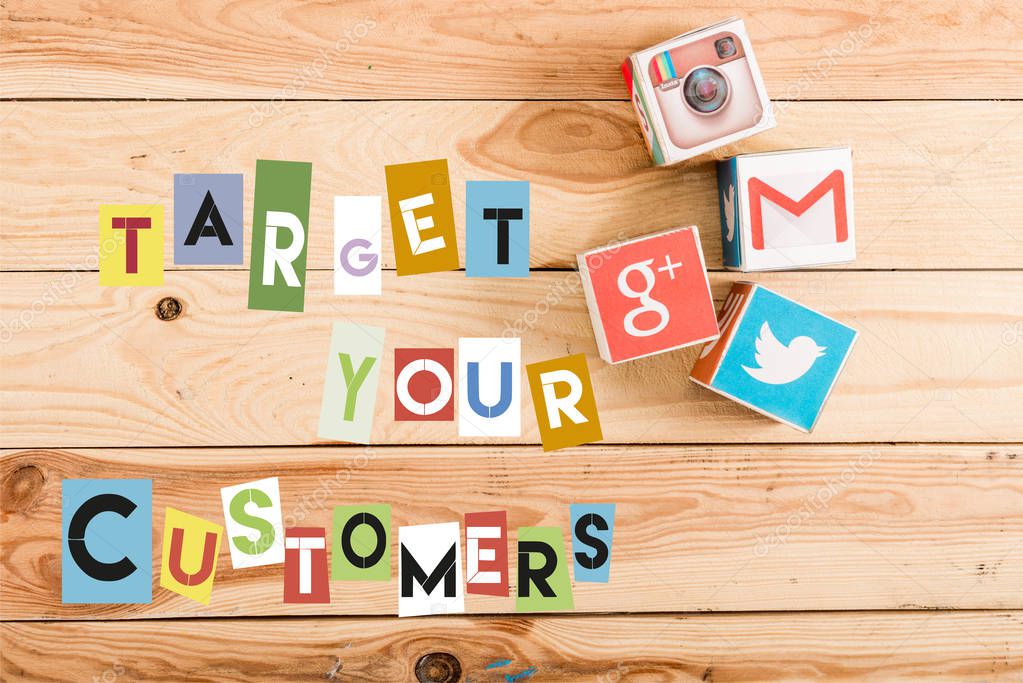 Top view of cubes with google plus, gmail, instagram and twitter logo on wooden table with target your customers lettering
