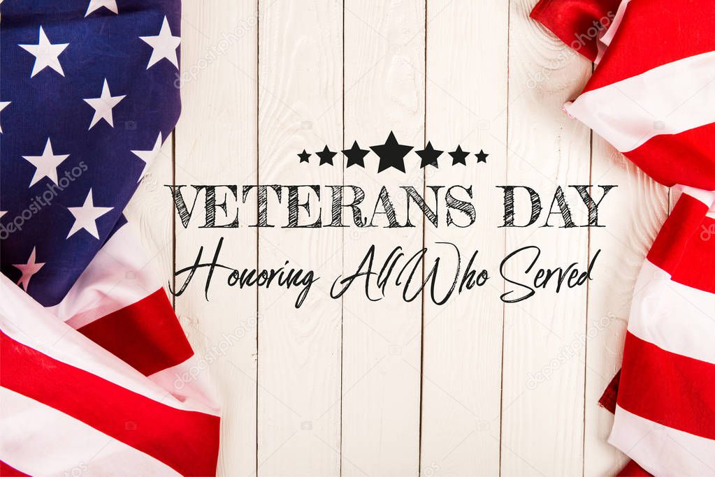 top view of american flags and veterans day lettering on white wooden surface