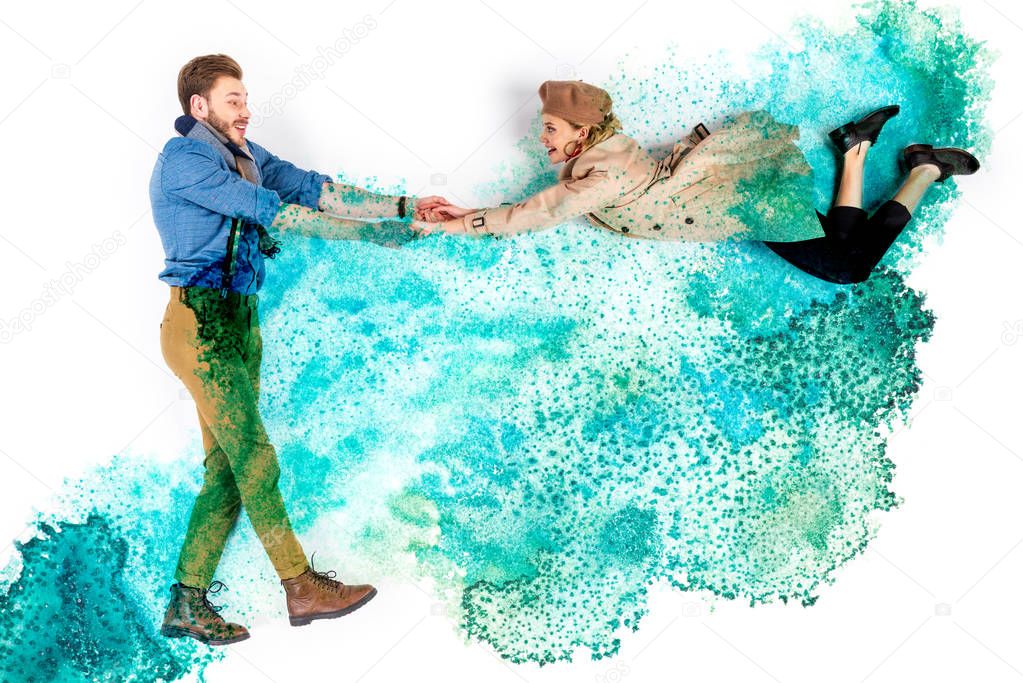 elegant woman levitating in air and holding hands with man on background with watercolor turquoise spills