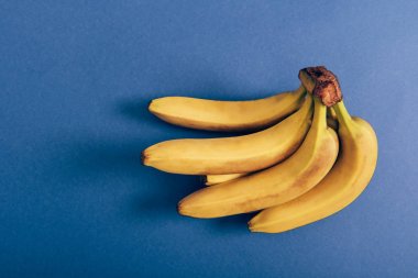 Top view of ripe bunch of delicious bananas on blue background clipart
