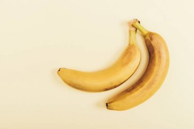 Top view of delicious and yellow bananas on light beige background clipart