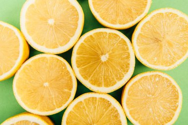 Close up view of bright yellow cut lemons on colorful green background clipart