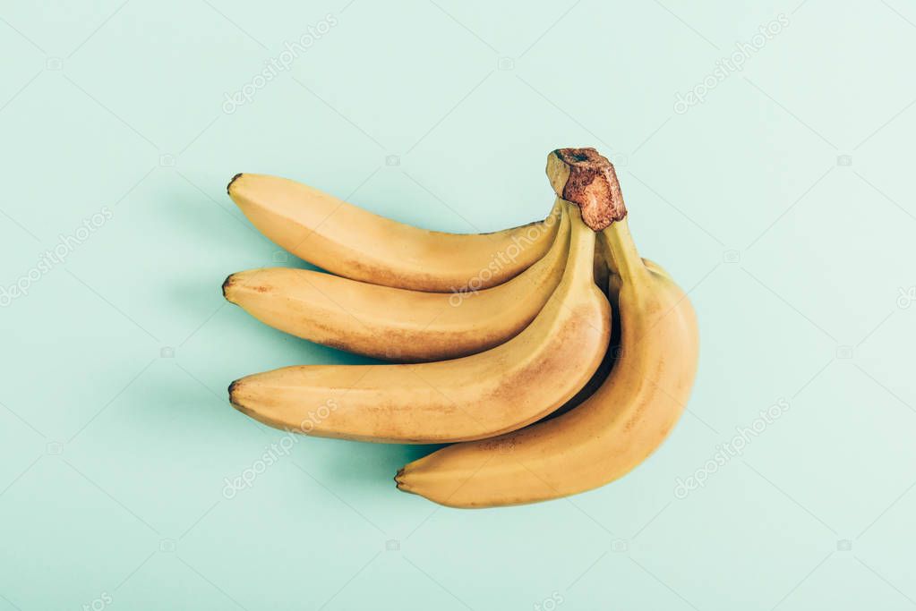 Bunch of ripe bright bananas on turquoise background