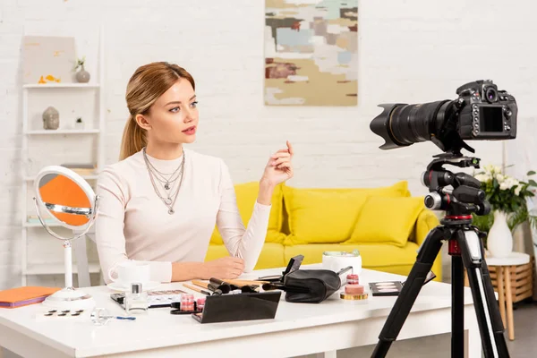 ビデオカメラの前で装飾化粧品とテーブルに座っている美容ブロガー — ストック写真