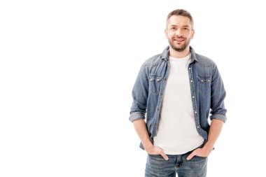 front view of smiling bearded man in denim shirt standing with hands in pockets isolated on white clipart