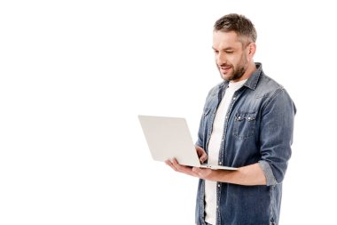 beyaz izole dizüstü bilgisayar kullanarak denim gömlek gülümseyen adam