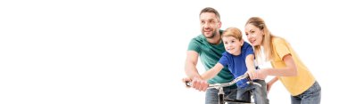 panoramic shot of smiling parents teaching son to ride bike isolated on white clipart