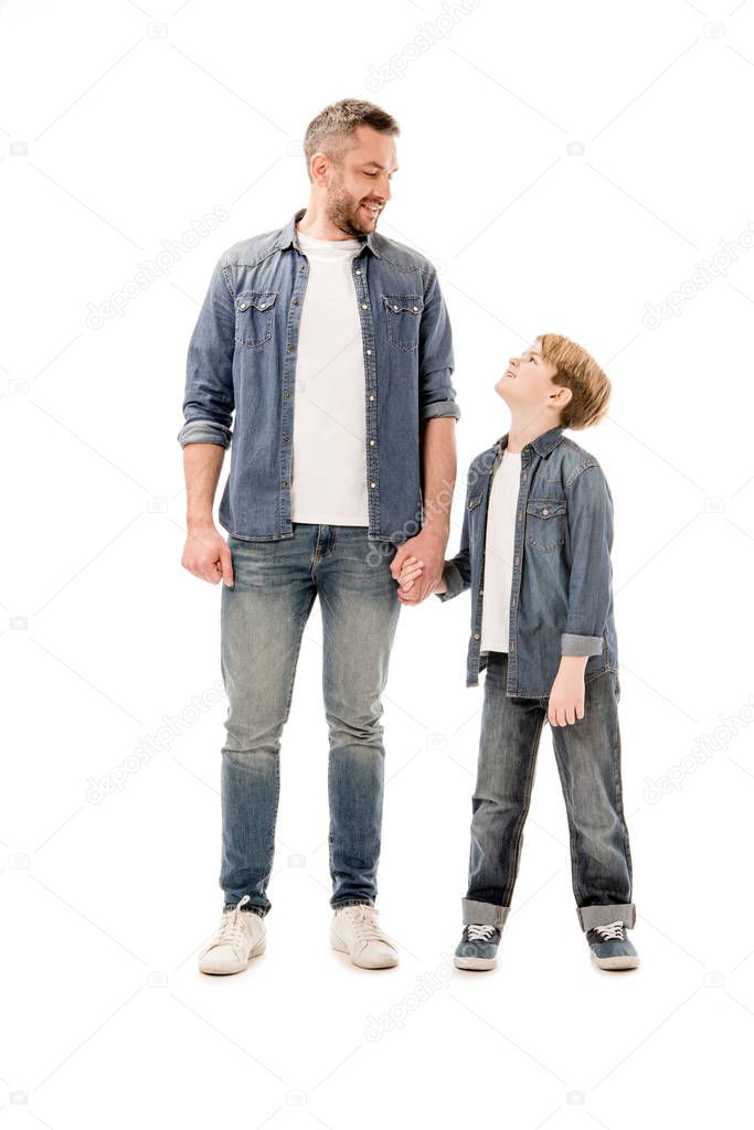 full length view of smiling son and father holding hands isolated on white