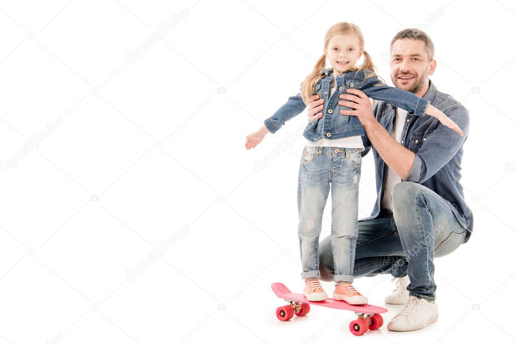 smiling father and daughter on skateboard isolated on white