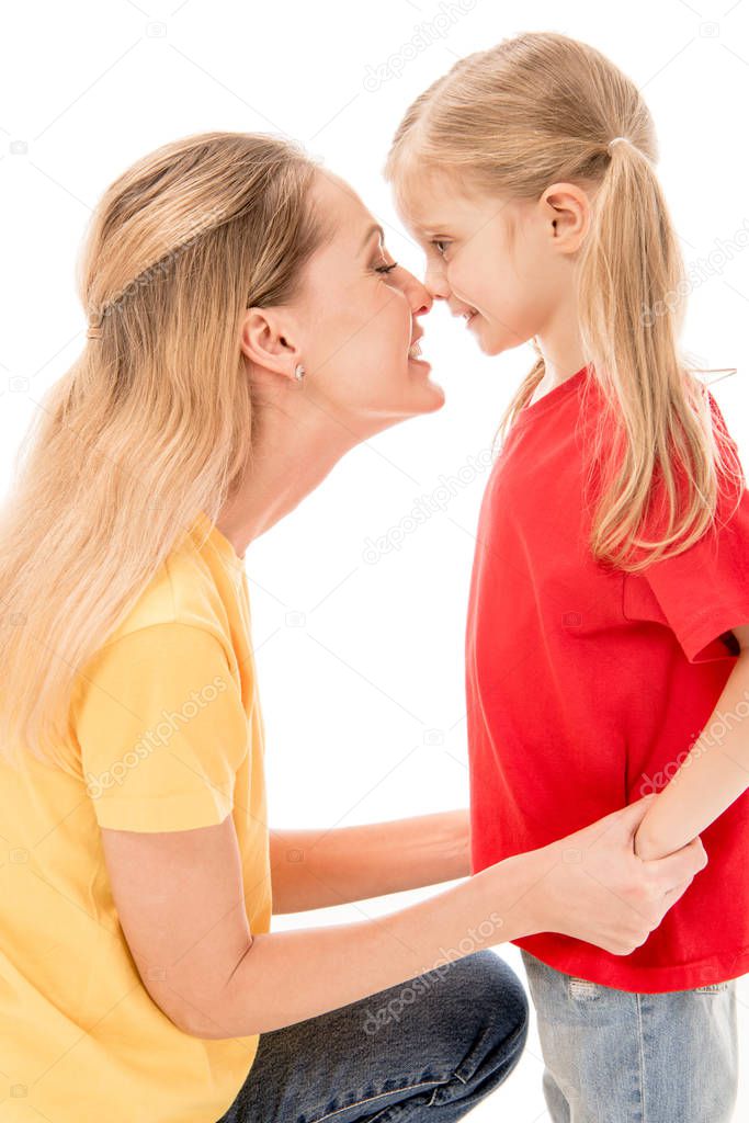 side view of happy mother and daughter holding hands and touching noses isolated on white