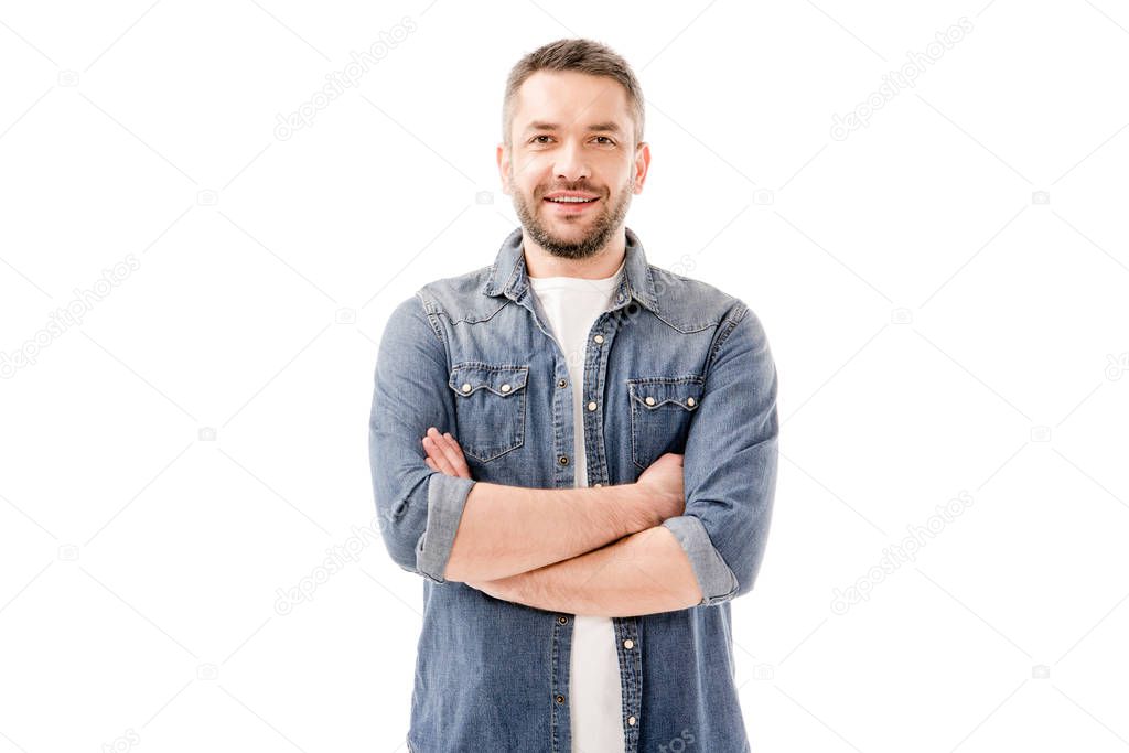 front view of smiling bearded man in denim shirt standing with crossed arms isolated on white