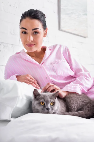 Portrait of woman with britain shorthair cat resting on bed at home — Stock Photo