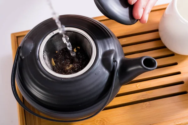 Tiro cortado de mulher fazendo chá enquanto tendo cerimônia de chá de manhã em casa — Fotografia de Stock