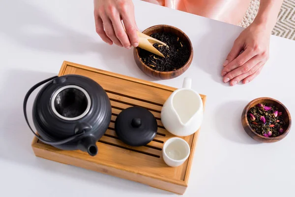 Tiro recortado de la mujer haciendo té mientras toma la ceremonia del té en la mañana en casa - foto de stock