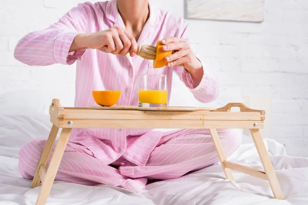 Visão parcial da mulher com pilão de madeira fazendo suco de laranja fresco na cama de manhã em casa — Fotografia de Stock