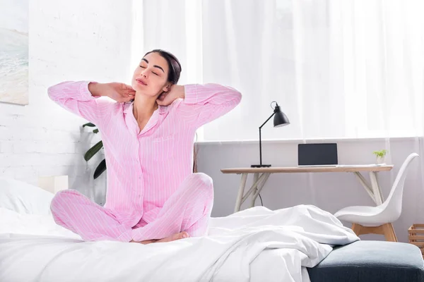Woman in pajamas stretching on bed in morning at home — Stock Photo