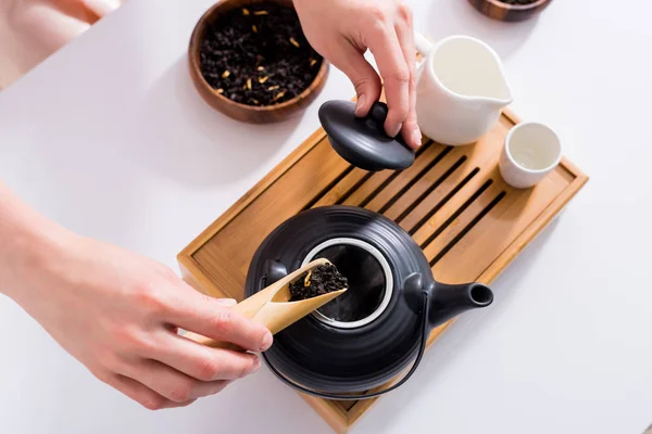 Tiro recortado de la mujer haciendo té mientras toma la ceremonia del té en la mañana en casa - foto de stock