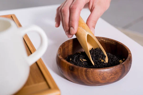 Tiro recortado de la mujer haciendo té mientras toma la ceremonia del té en la mañana en casa - foto de stock