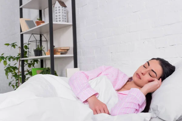 Retrato de mulher de pijama rosa dormindo na cama em casa — Fotografia de Stock