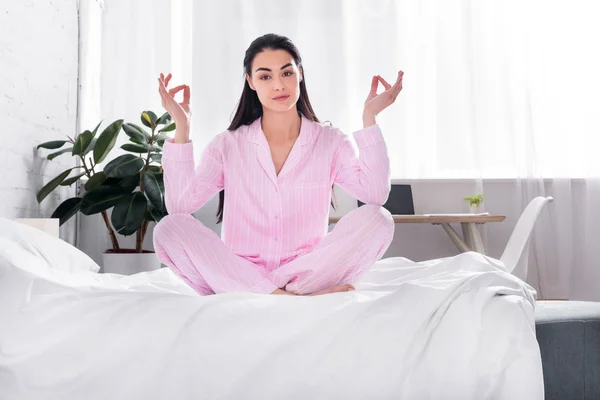 Mulher de pijama rosa sentado em lótus posar na cama de manhã em casa — Fotografia de Stock