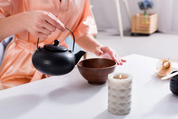 Tiro recortado de la mujer haciendo té mientras toma la ceremonia del té en la mañana en casa - foto de stock