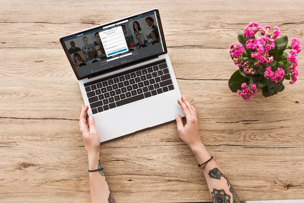 Partial view of woman at tabletop with laptop with linkedin logo and kalanhoe plant in flowerpot — Stock Photo