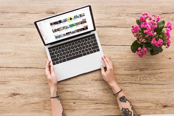 Visão parcial da mulher na mesa com laptop com site do youtube e planta kalanhoe em vaso de flores — Fotografia de Stock