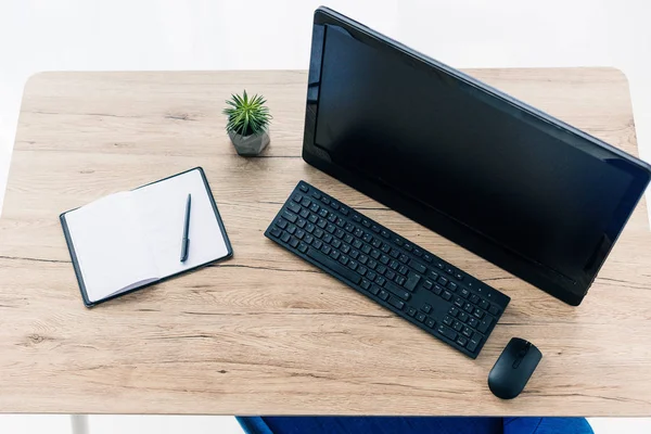 Erhöhter Blick auf leeres Lehrbuch, Topfpflanze und Computer auf Holztisch — Stockfoto