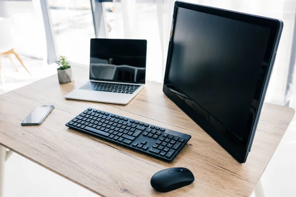 Vista de primer plano de la computadora, computadora portátil, teléfono inteligente y planta en maceta en la mesa - foto de stock