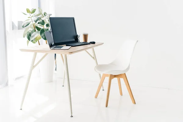 Interno del posto di lavoro con sedia, computer portatile, computer, tazza di carta di caffè sul tavolo — Foto stock