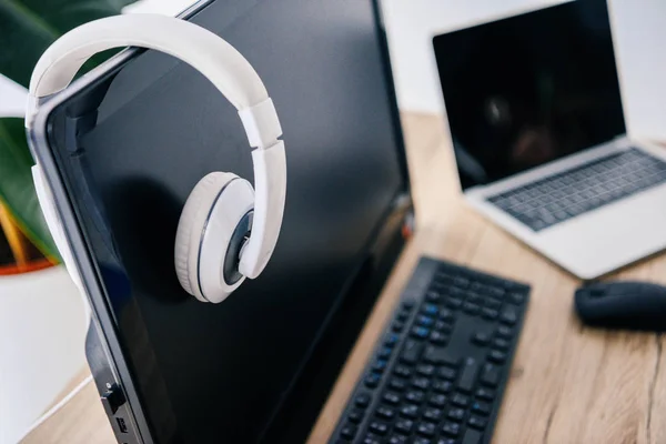 Vista de primer plano de los auriculares en la computadora y el ordenador portátil en la mesa - foto de stock